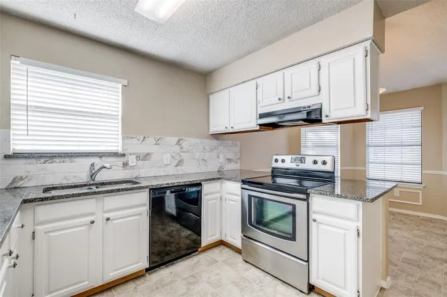 a kitchen with granite countertop white cabinets and white appliances