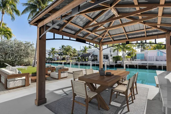a view of patio with table and chairs potted plants and floor to ceiling window