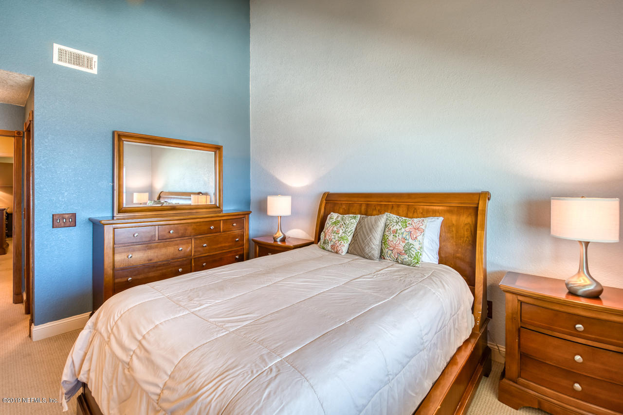 8550 A1A South, Unit 408 St. Augustine, FL 32080 - Photo 15 of 33 a bedroom with a bed and a lamp on dresser