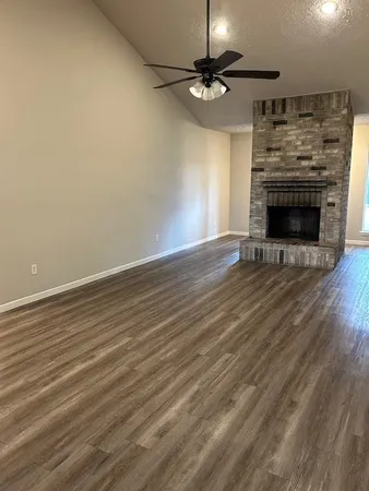 an empty room with wooden floor a fireplace a chandelier and wooden floor