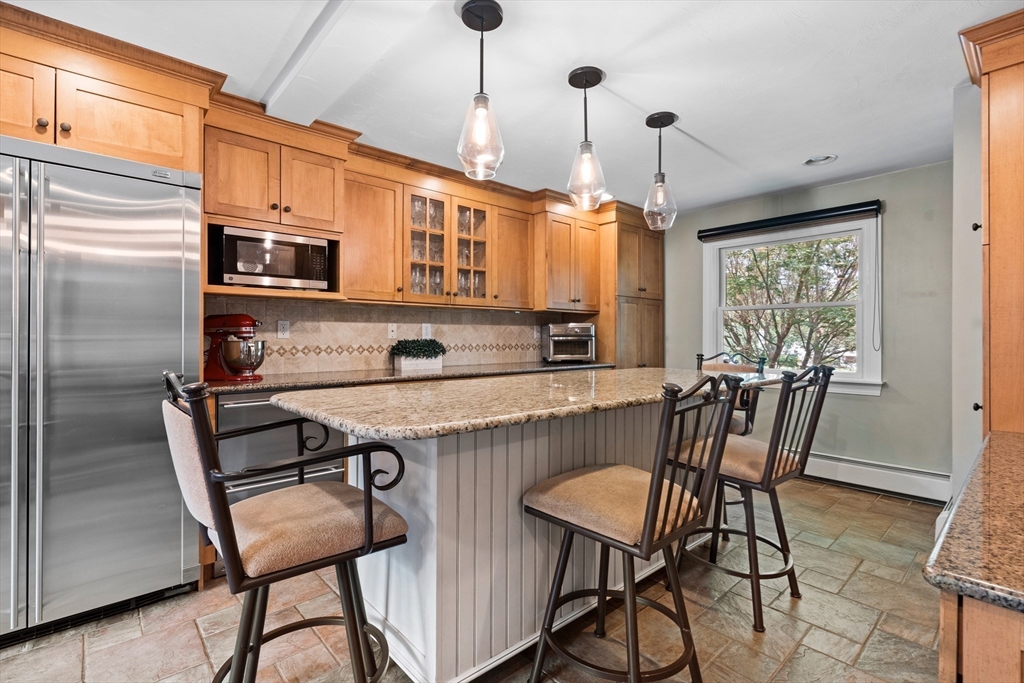 27 Pleasant Street Millis, MA 02054 - Photo 15 of 42 a kitchen with stainless steel appliances granite countertop a stove top oven a refrigerator a dining table and chairs with wooden floor