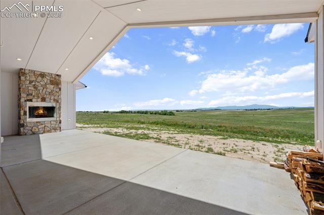 24365 Murphy Road Calhan, CO 80808 - Photo 42 of 48 View of patio / terrace with an outdoor stone fireplace, a rural view, and a mountain view