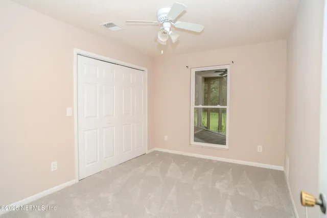 an empty room with fan and windows