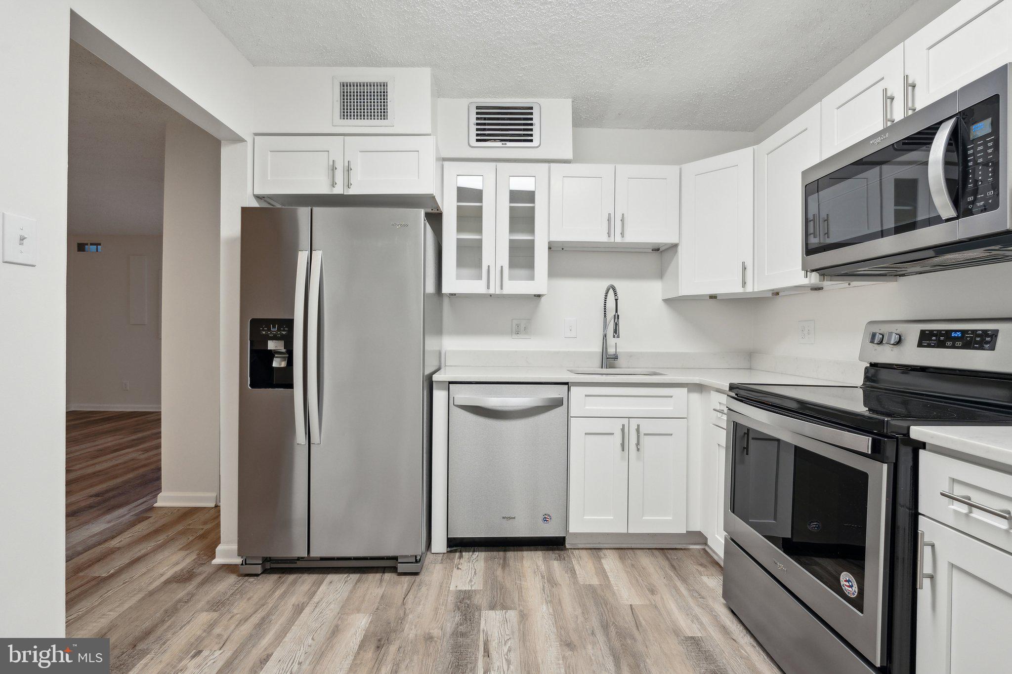 1800 Old Meadow Road, Unit 115 McLean, VA 22102 - Photo 15 of 35 a kitchen with stainless steel appliances granite countertop a refrigerator stove and white cabinets