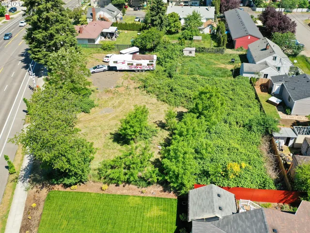 an aerial view of residential houses with outdoor space and trees all around
