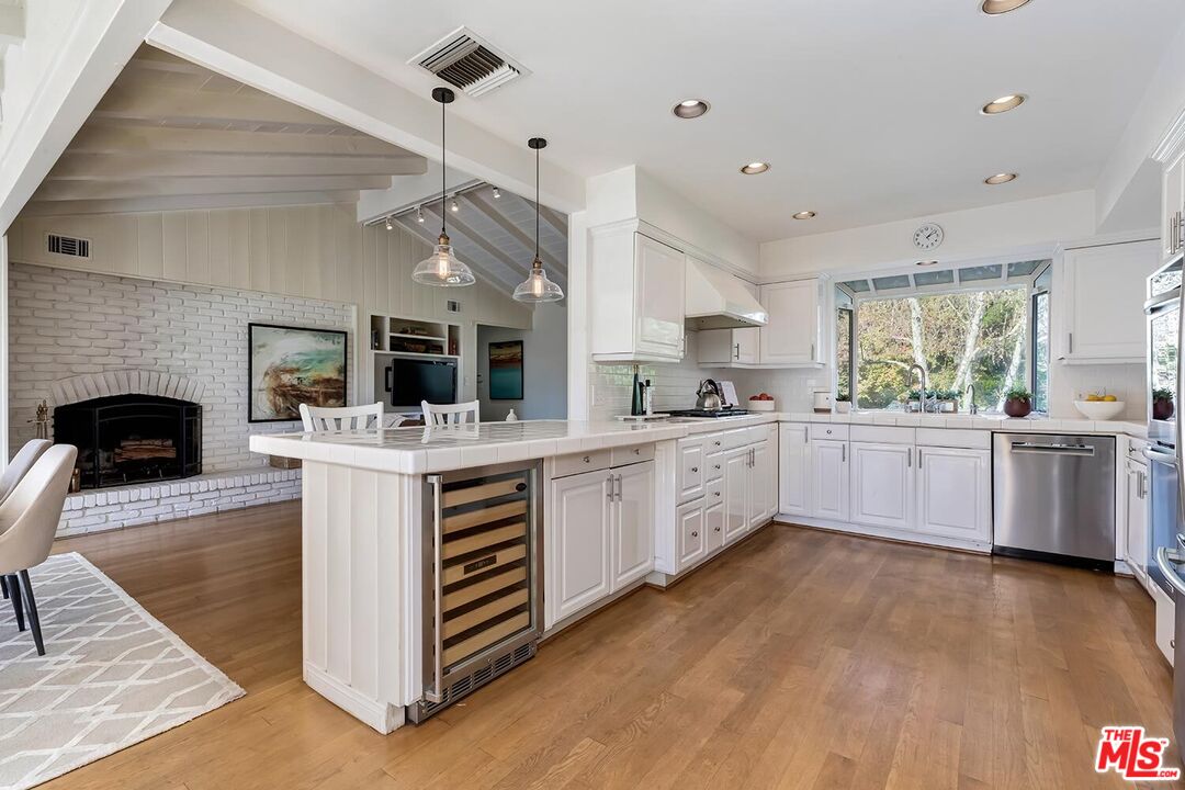 751 Teakwood Road Los Angeles, CA 90049 - Photo 20 of 46 a kitchen with stainless steel appliances kitchen island granite countertop a stove top oven a sink dishwasher and a fireplace