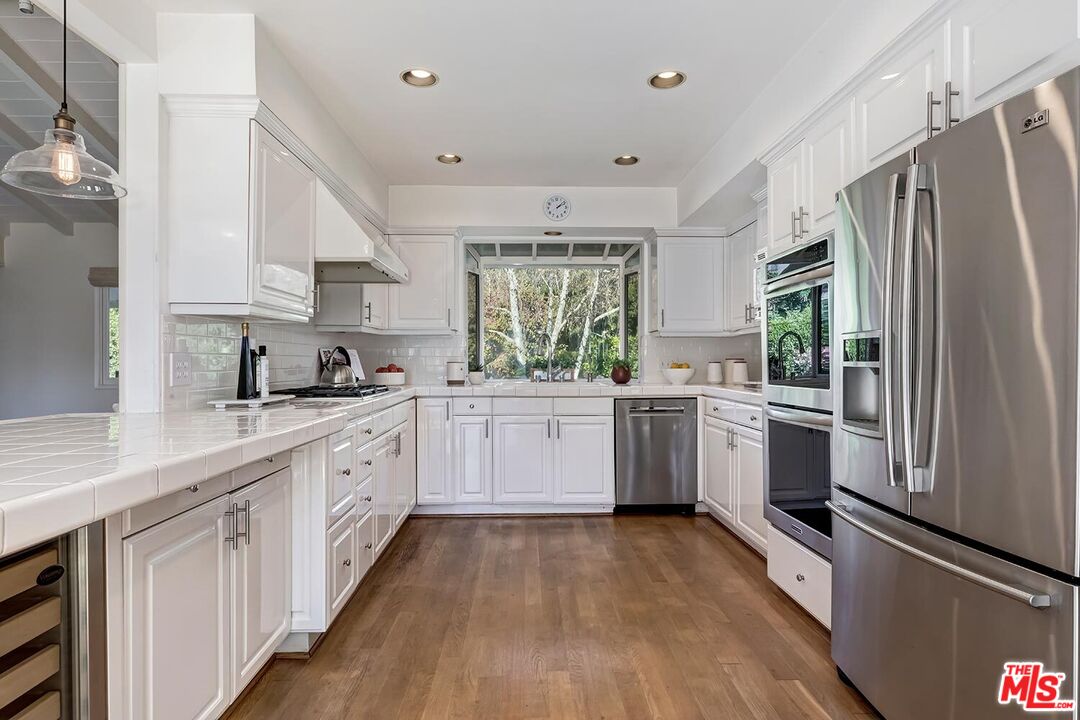 751 Teakwood Road Los Angeles, CA 90049 - Photo 21 of 46 a kitchen with white cabinets and white appliances