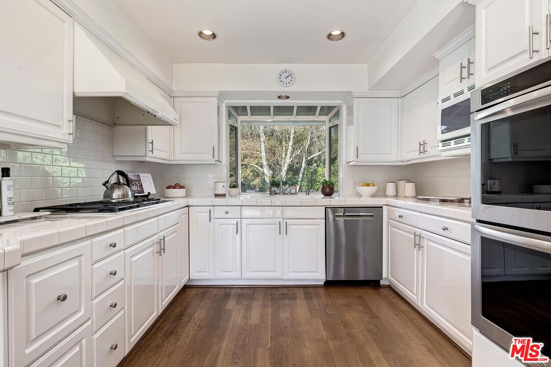 751 Teakwood Road Los Angeles, CA 90049 - Photo 22 of 46 a kitchen with white cabinets and white appliances