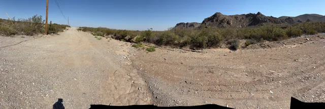 a view of a dry yard with mountains in the background