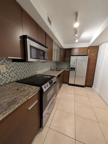 a kitchen with stainless steel appliances granite countertop a sink and a stove top oven with wooden floor