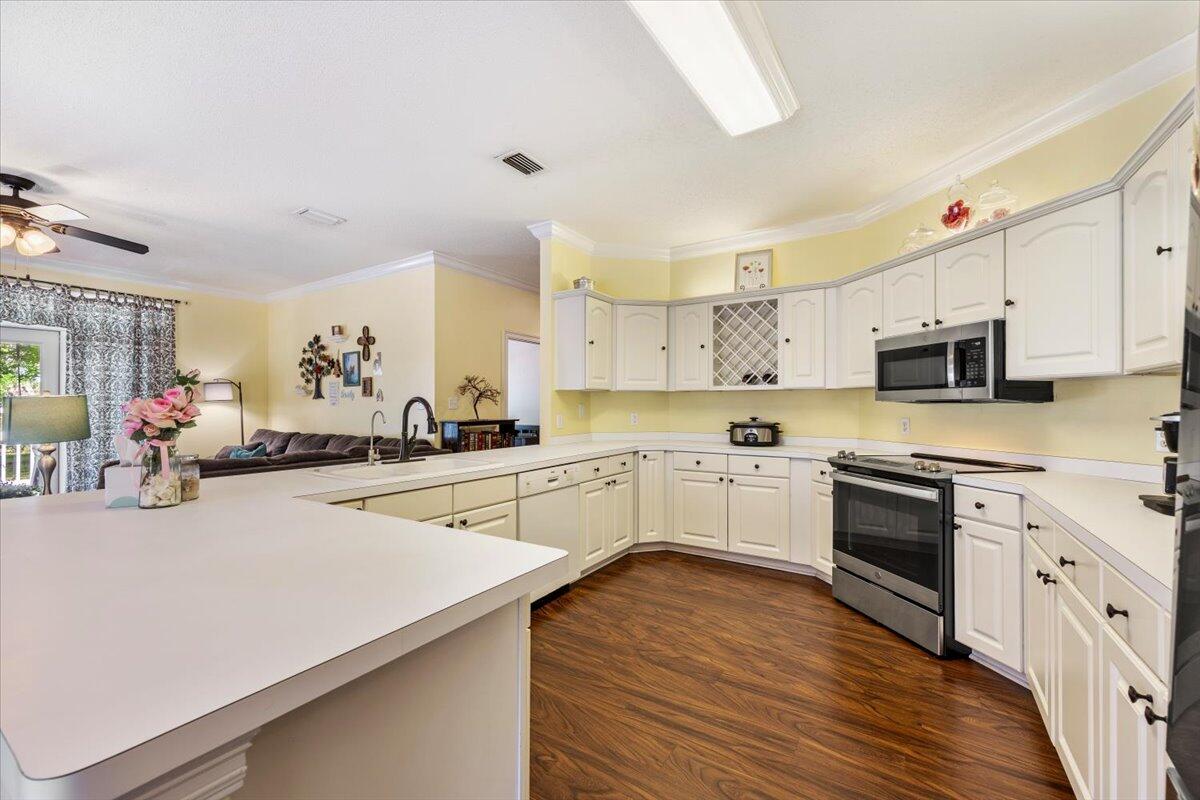 1830 Seahawk Lane Navarre, FL 32566 - Photo 17 of 53 a kitchen with stainless steel appliances a sink dishwasher stove refrigerator and white cabinets with wooden floor