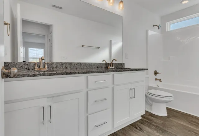a bathroom with a toilet sink double vanity and mirror