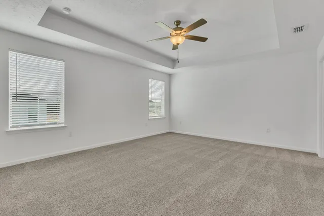 an empty room with windows and fan