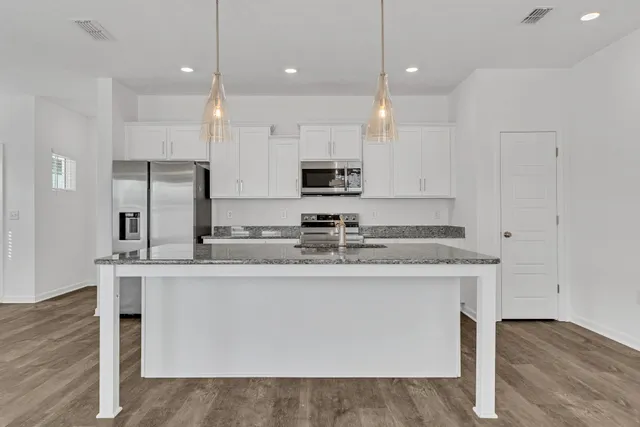 a kitchen with kitchen island granite countertop a sink a center island stainless steel appliances and cabinets