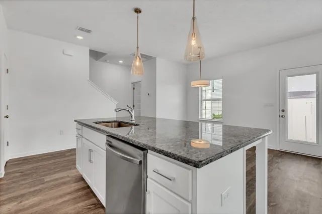 a kitchen with granite countertop a sink a counter space appliances and a floor
