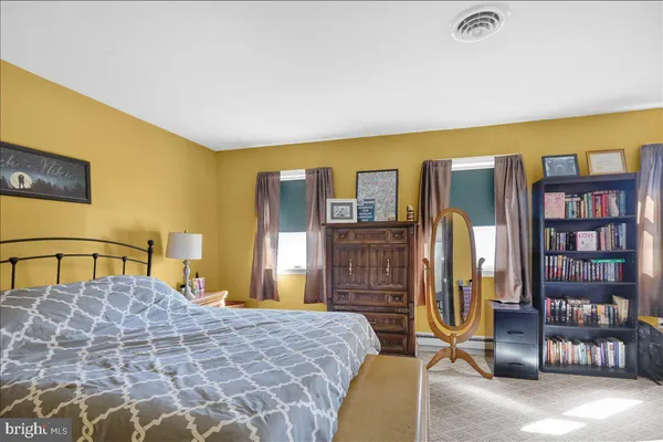 a bedroom with a bed and dresser with wooden floor