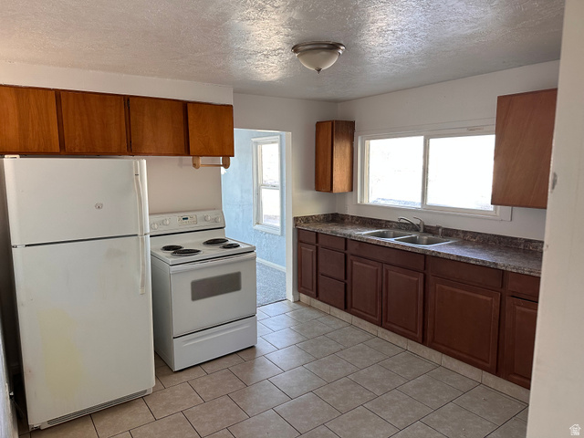 154 East Harris Street Ogden, UT 84401 - Photo 4 of 10 Kitchen with white appliances, wood finish cabinetry, dark countertops, a textured ceiling, and light tile patterned flooring