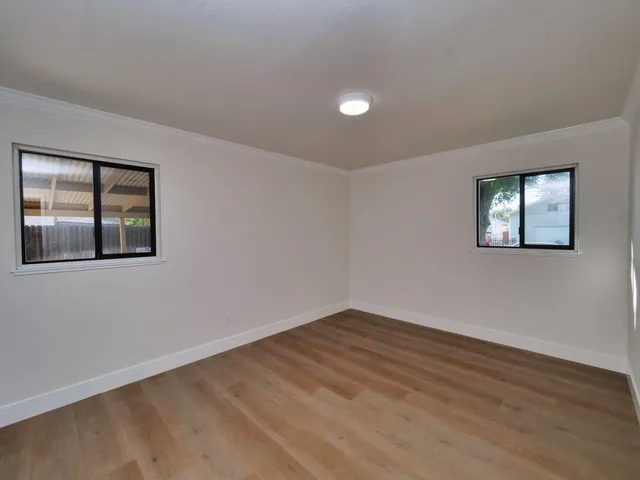 a view of an empty room with wooden floor and a window