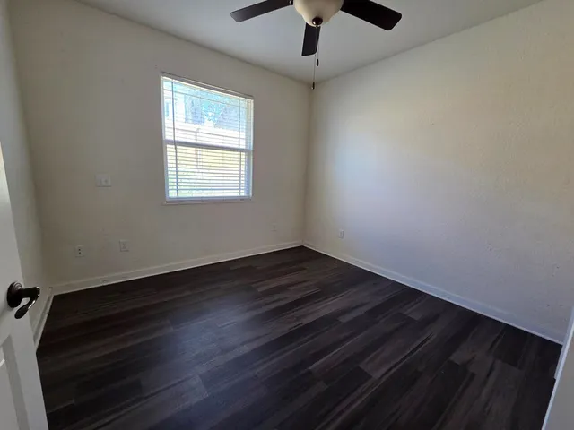 an empty room with wooden floor cabinet and windows