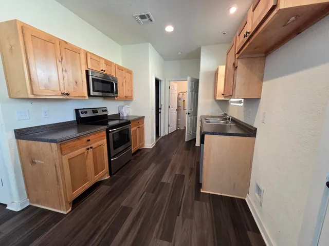 a kitchen with stainless steel appliances granite countertop a stove a sink and a refrigerator
