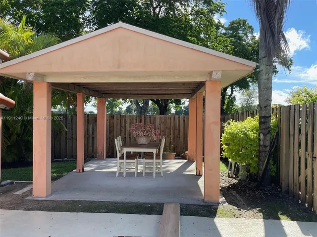 a patio with table and chairs and potted plants