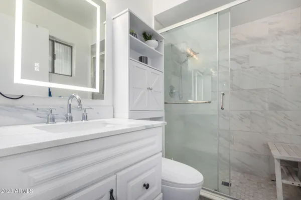 a bathroom with a granite countertop sink toilet a mirror and shower