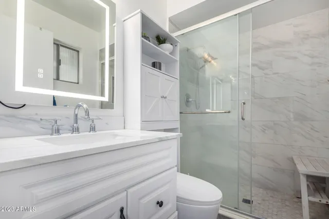 a bathroom with a granite countertop sink toilet a mirror and shower