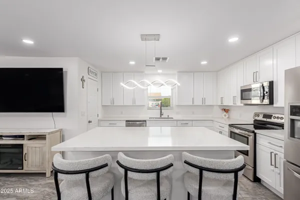 a kitchen with microwave a stove and chairs