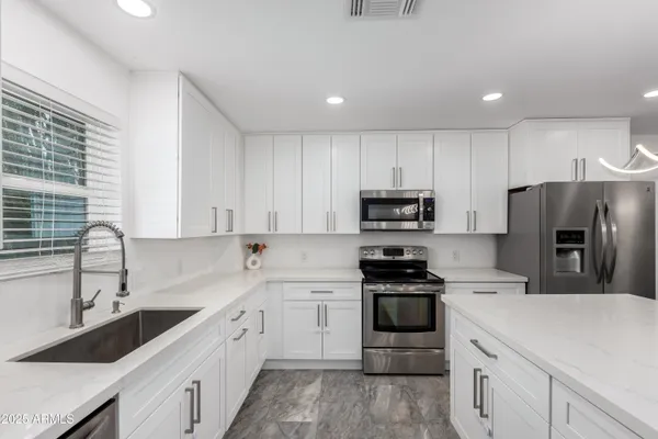 a kitchen with a sink white cabinets and stainless steel appliances