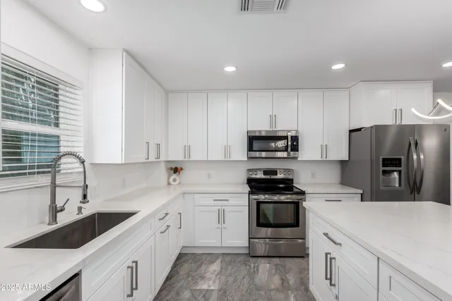 a kitchen with a sink white cabinets and stainless steel appliances