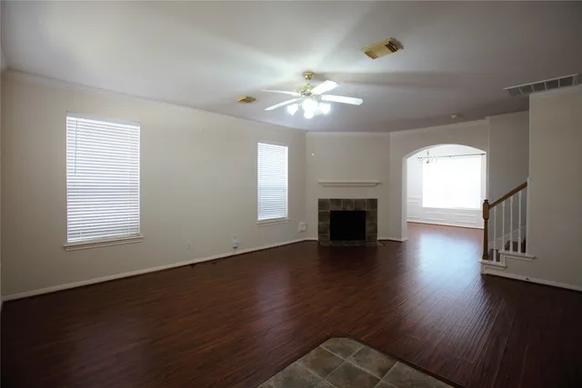 an empty room with wooden floor fireplace and windows