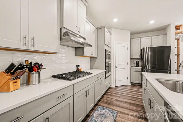 a kitchen with stainless steel appliances a refrigerator a sink and white cabinets