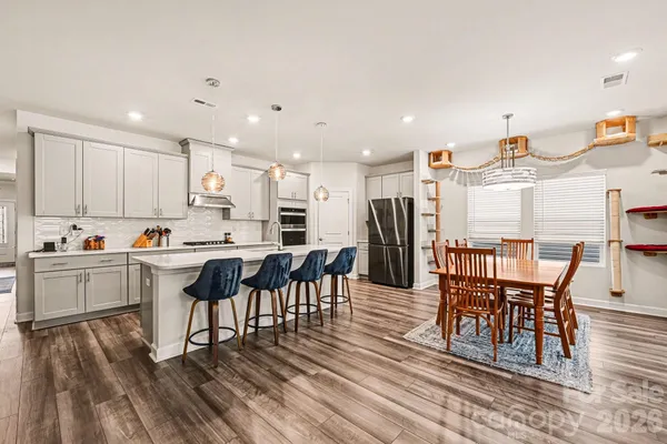 a kitchen with stainless steel appliances kitchen island granite countertop a table chairs sink and cabinets