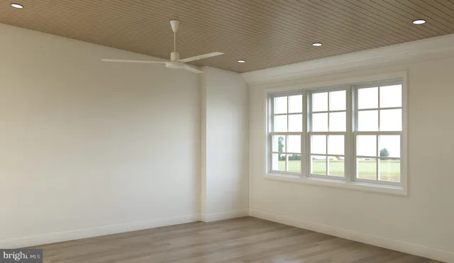 an empty room with wooden floor ceiling fan and windows