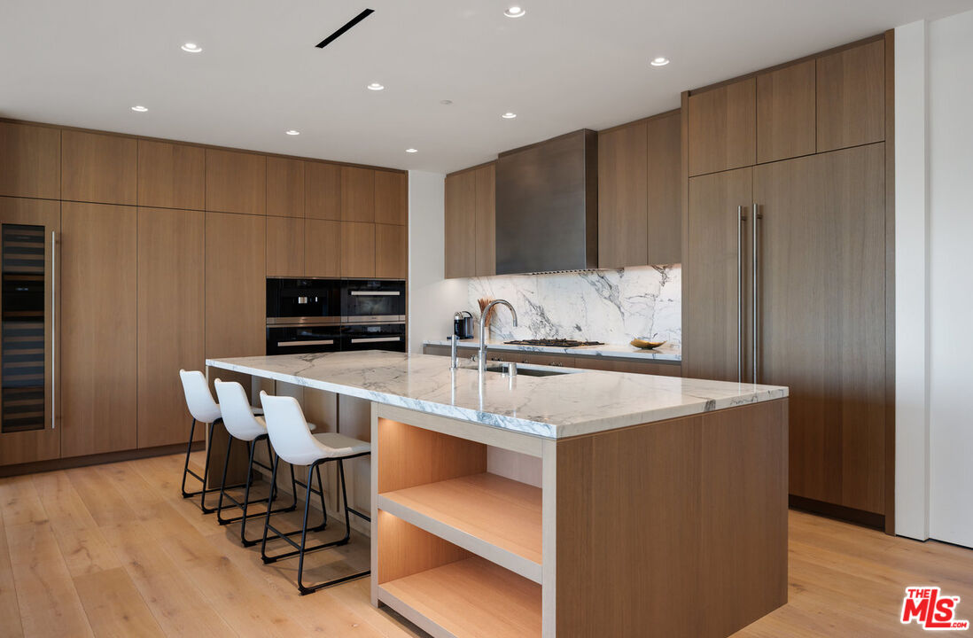 8899 Beverly Boulevard, Unit 6G Los Angeles, CA 90048 - Photo 8 of 25 a kitchen with kitchen island a sink table and chairs
