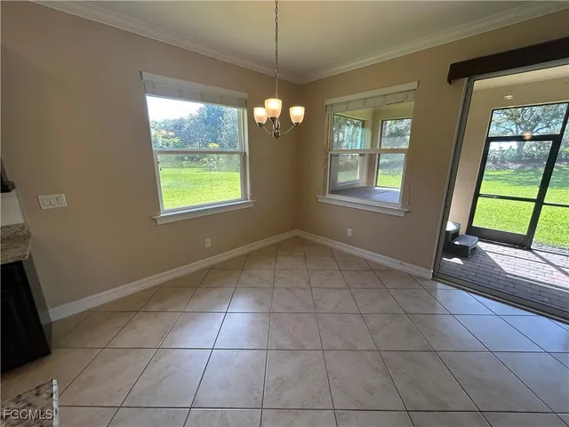 a view of an empty room with window and chandelier fan