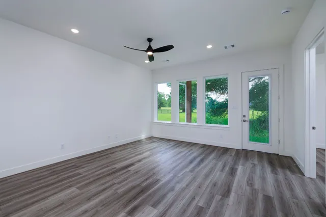 an empty room with wooden floor and windows