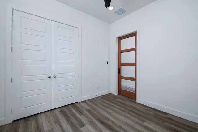 an empty room with wooden floor a ceiling fan and windows