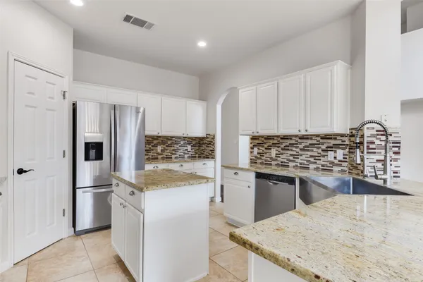 a kitchen with granite countertop a sink stove and refrigerator