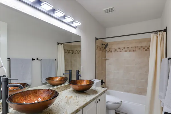 a bathroom with a granite countertop sink a toilet a shower and a mirror