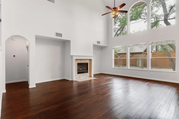 an empty room with wooden floor fireplace and windows