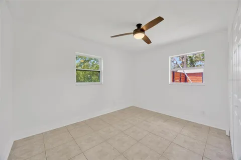 an empty room with windows and a ceiling fan
