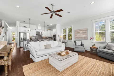 a living room with furniture kitchen view and a wooden floor