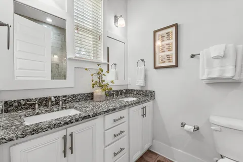 a bathroom with a granite countertop sink and a toilet