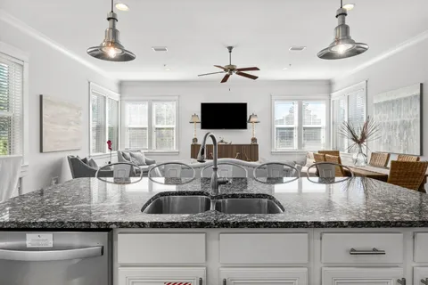 a kitchen with granite countertop a sink a counter top space and living room view