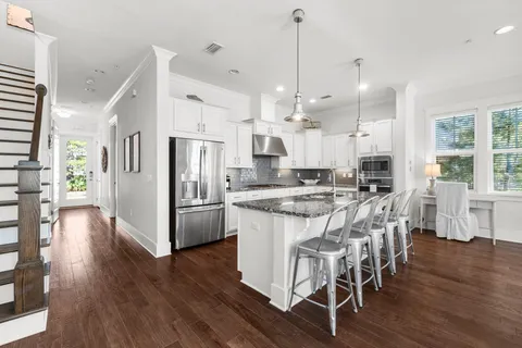 a kitchen with stainless steel appliances kitchen island wooden floors stove and white cabinets