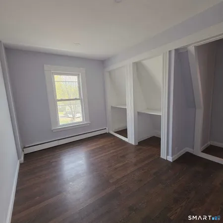 an empty room with wooden floor closet and windows