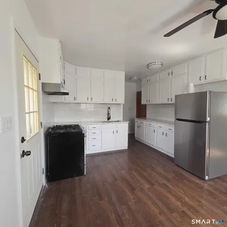 a kitchen with granite countertop white cabinets and refrigerator