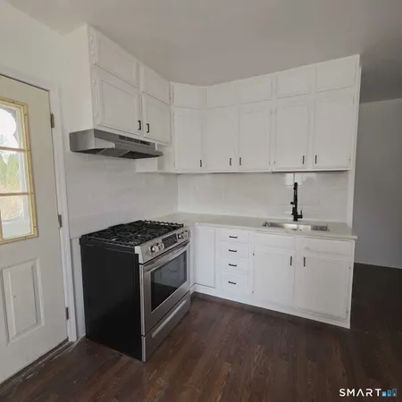 a kitchen with white cabinets and a stove with wooden floor