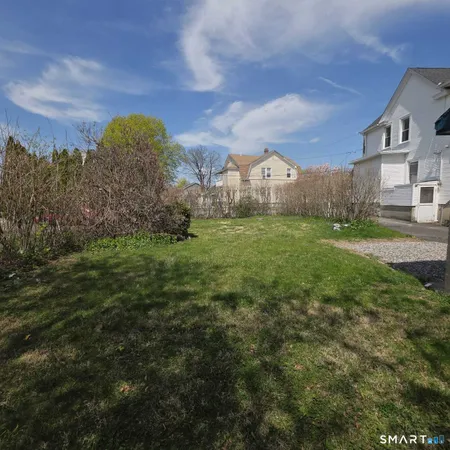 a view of a big house with a big yard and large trees